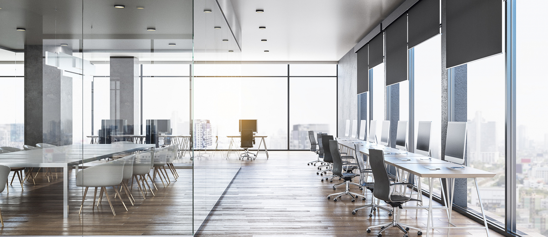 open, empty office space with glass walls and wooden floors. desks are lined up against the floor-to ceiling windows giving way for more space in between things